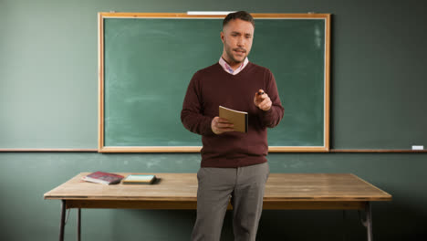 Male-Teacher-In-School-Classroom-Standing-In-Front-Of-Board-Teaching-Lesson