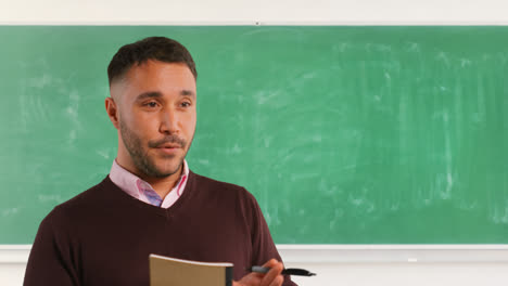 Close-Up-Shot-Of-Mature-Male-Teacher-In-Classroom-Standing-In-Front-Of-Board-Teaching-Lesson