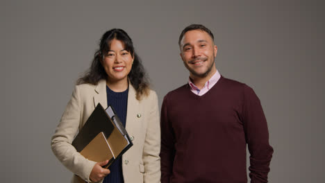 Retrato-De-Estudio-De-Profesores-Hombres-Y-Mujeres-Sonrientes-Caminando-Hacia-La-Cámara-Y-Hablando-Contra-Un-Fondo-Gris.