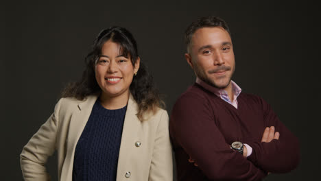 Retrato-De-Estudio-De-Profesores-Hombres-Y-Mujeres-Sonrientes-De-Pie-Sobre-Un-Fondo-Negro