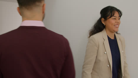 Male-And-Female-Teachers-Passing-As-They-Walk-Along-Corridor-In-School-Building-Together-1