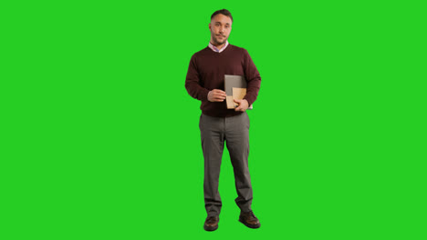 Full-Length-Studio-Portrait-Of-Mature-Male-Teacher-Or-Businessman-Standing-Against-Green-Screen-Carrying-Folder