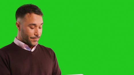 Close-Up-Studio-Shot-Of-Male-Teacher-Or-Businessman-Standing-Against-Green-Screen-Reading-Document