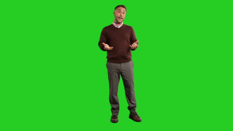 Full-Length-Studio-Portrait-Of-Mature-Male-Teacher-Talking-To-Class-Standing-Against-Green-Screen