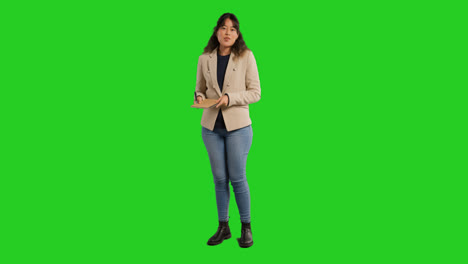 Full-Length-Studio-Portrait-Of-Female-Teacher-With-Notebook-Talking-To-Class-Standing-Against-Green-Screen-1