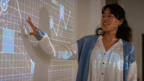 Female-Teacher-Giving-Maths-Or-Science-Lesson-In-College-Or-University-Standing-At-The-Front-Of-Class-With-Projection-Of-Graph-5