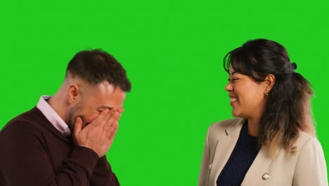 Close-Up-Studio-Shot-Of-Male-And-Female-Teachers-Or-Businesspeople-Laughing-Together-Against-Green-Screen