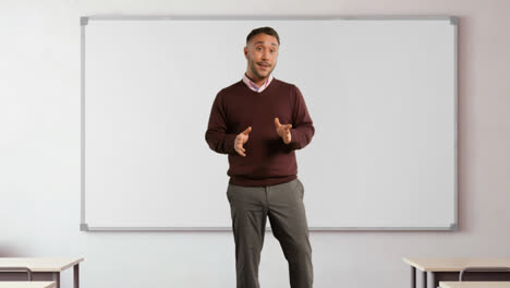 Mature-Male-Teacher-In-Classroom-Standing-In-Front-Of-Board-Teaching-Lesson-In-School