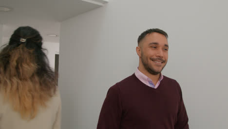 Male-And-Female-Teachers-Passing-As-They-Walk-Along-Corridor-In-School-Building-Together