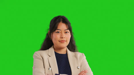 Close-Up-Studio-Portrait-Of-Female-Teacher-Or-Businesswoman-Standing-Against-Green-Screen-Folding-Arms