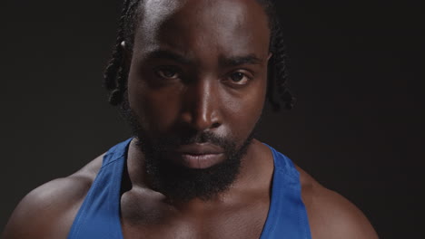 Close-Up-Portrait-Of-Serious-Male-Boxer-Wearing-Vest-Walking-Towards-Camera-And-Into-Focus-Training-For-Sports-Event-Against-Black-Studio-Background-2