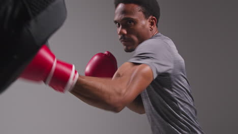 Studioaufnahme-Eines-Männlichen-Boxers-Beim-Sparring-Mit-Einem-Trainer,-Der-Schlagpolster-Oder-Handschuhe-Trägt-Und-Für-Den-Kampf-übt-6