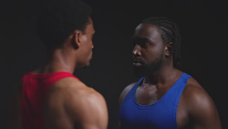 Close-Up-Of-Two-Male-Boxers-Going-Face-To-Face-Before-Boxing-Match-Staring-At-Opponent-Against-Black-Background-1