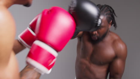 Real-Time-Action-Studio-Shot-Of-Two-Male-Boxers-Wearing-Gloves-Fighting-In-Boxing-Match-Against-Grey-Background-4