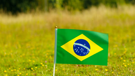 Close-Up-Of-Small-Brazilian-National-Flag-Outdoors-In-Countryside-Field-Or-Garden-Moving-In-Wind