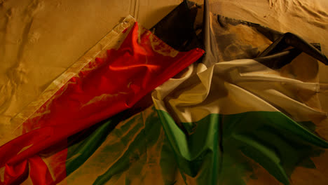 Overhead-Studio-Shot-Showing-Person-Unfolding-National-Flag-Of-UAE-United-Arab-Emirates-On-Sandy-Desert-Background