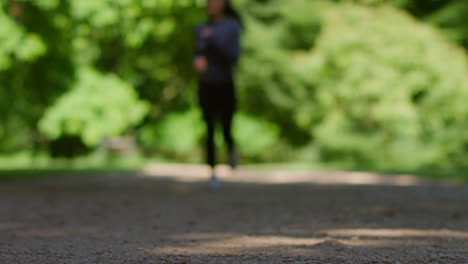 Toma-A-Nivel-Del-Suelo-De-Una-Mujer-Joven-Haciendo-Ejercicio-Corriendo-Hacia-La-Cámara-En-Foco-En-Un-Parque-De-La-Ciudad-1