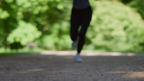 Aufnahme-Einer-Jungen-Frau-Auf-Bodenhöhe-Beim-Training,-Die-Im-Stadtpark-2-Auf-Die-Kamera-Zuläuft-Und-Scharfgestellt-Wird