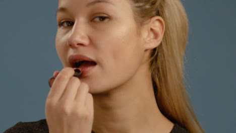 CU-Woman-Applies-Lipstick-Facing-Camera