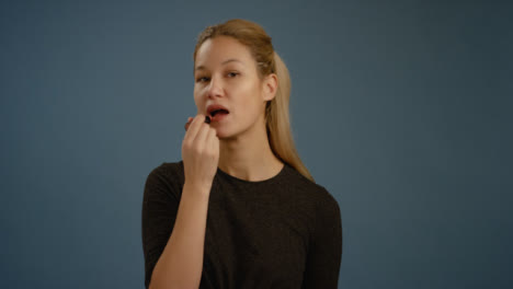 Woman-Applies-Lipstick-Facing-Camera