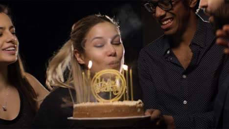 Mujer-joven-apaga-velas-de-pastel-de-cumpleaños
