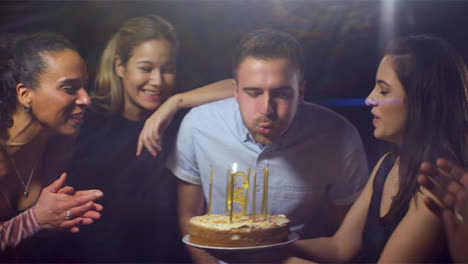 Man-Blows-Out-Birthday-Cake-Candles-with-Friends