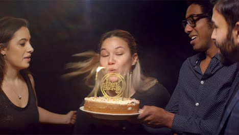 Woman-Blows-Out-Birthday-Cake-Candles