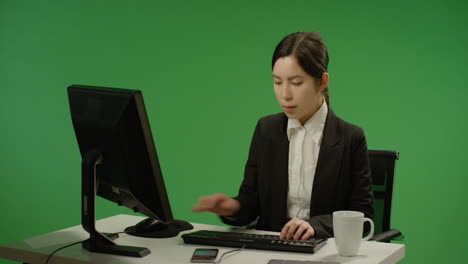 Empresaria-sentado-en-el-escritorio-escribiendo-en-pantalla-verde
