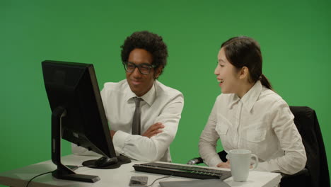 Two-colleagues-look-at-computer-and-smile-on-green-screen