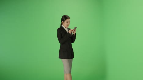 Smiling-woman-typing-on-phone-with-green-screen