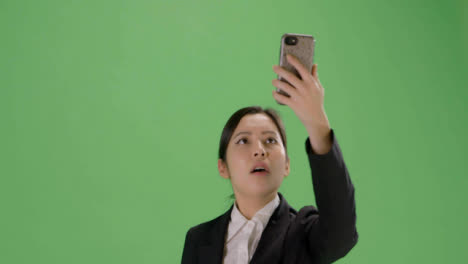 CU-Businesswoman-trying-find-phone-signal-on-green-screen
