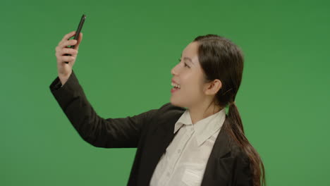 Smiling-Businesswoman-Taking-Seflie-on-Green-