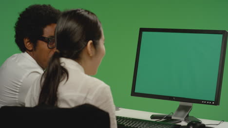 Colleagues-look-at-computer-and-smile-on-green-screen