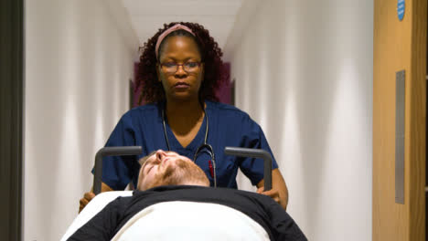 Female-médico-staff-wheeling-patient-in-hospital-bed