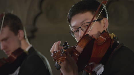 Close-Up-Of-Three-Violinists-Playing-Together-During-A-Performance