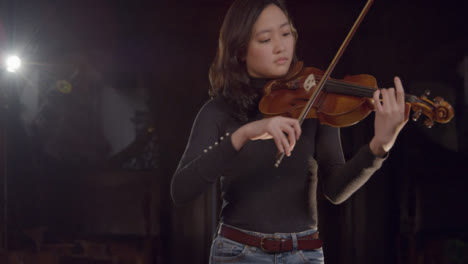 Vista-frontal-de-la-mujer-violinista-tocando-durante-el-ensayo