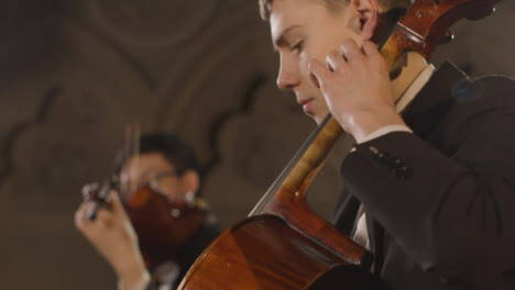 CU-violonchelista-masculino-durante-la-actuación-con-cuarteto-de-cuerda