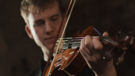 Cerca-de-violinista-masculino-mano-y-arco-durante-el-rendimiento