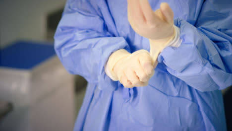 Cu-Medizinischer-Mitarbeiter-Zieht-OP-Handschuh-An