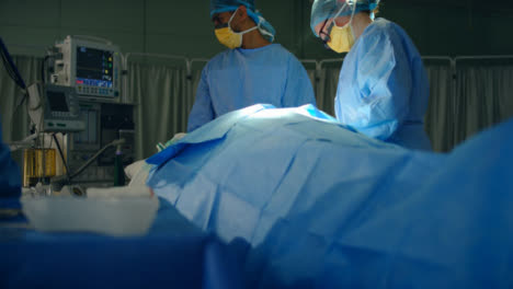 Pan-Medical-Staff-Look-at-Monitor-During-Surgery