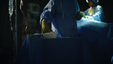 Arzthelferin,-Die-Chirurgisches-Instrument-In-Dunkler-Chirurgie-Aufhebt