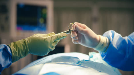 CU-Hand-Passing-Medical-Scissors-Over-Operating-Bed