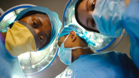médico-Staff-Looking-Down-at-Patient-in-Surgery-and-Discussing