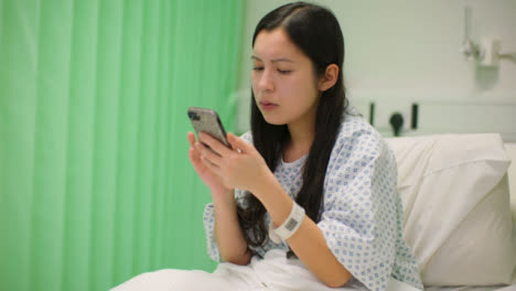 Concerned-Hospital-Patient-Sits-Up-Using-Phone