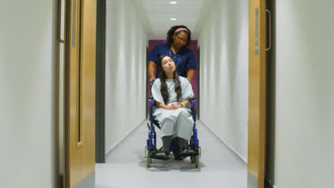 Enfermera-empuja-al-paciente-en-silla-de-ruedas-por-el-pasillo