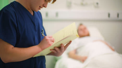 Krankenpfleger-Im-Gespräch-Mit-Dem-Patienten,-Der-Notizen-Auf-Der-Karte-Macht
