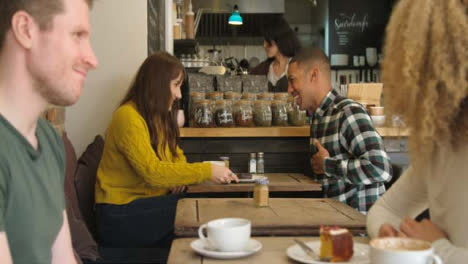 Dos-parejas-hablando-y-riéndose-de-las-mesas-en-el-café