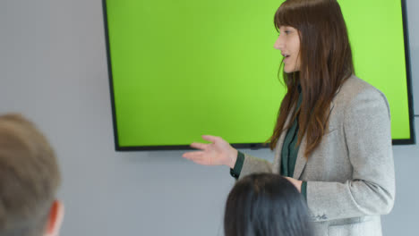 Mujer-de-negocios-que-presenta-a-sus-colegas-usando-tv-de-pantalla-verde
