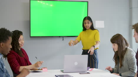 Woman-Leading-Meeting-Colleagues-With-Green-Screen-Tv