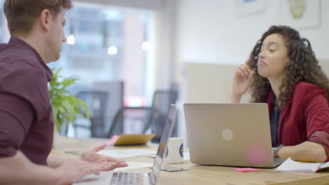 Man-And-Woman-Talking-In-Modern-Office-Space